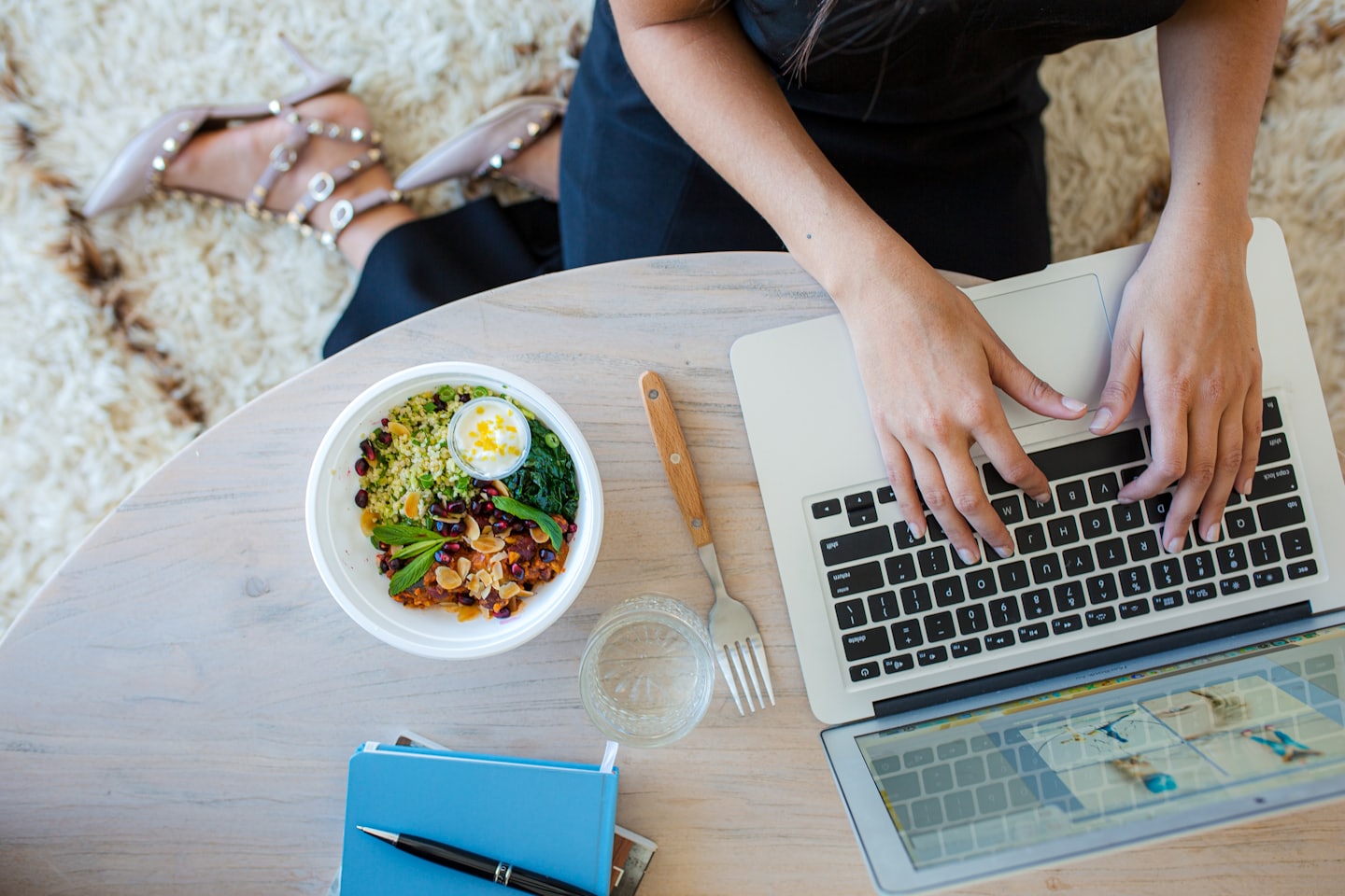 Person typing on a laptop at a table with lunch.