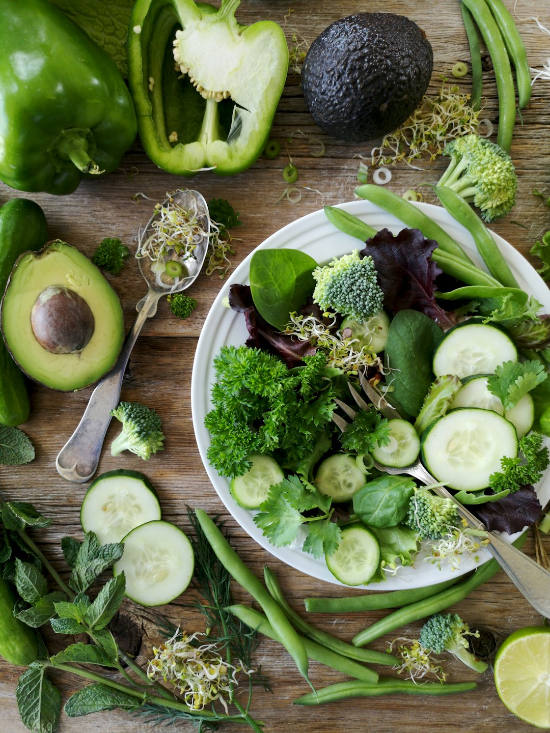 Fresh green vegetables artfully arranged on a wooden table.