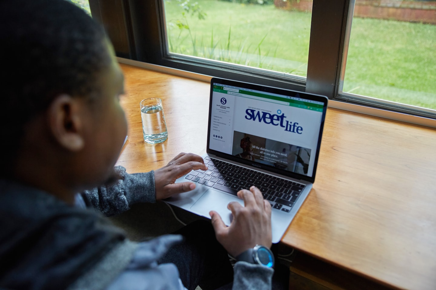 Person typing on a laptop at a counter with a window.