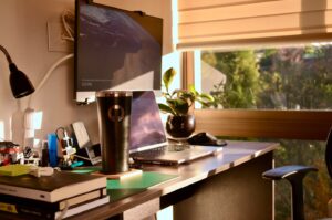 Laptop and satellite image on sunlit home office desk.